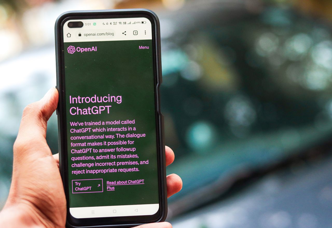 Gros plan sur un smartphone affichant les détails de ChatGPT sur le site web d’OpenAI, tenu par une personne.